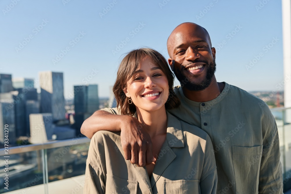 Naklejka premium Smiling couple on a rooftop skyline portrait background with city view for social media and lifestyle use