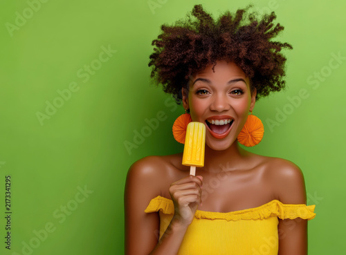 Young woman enjoying a yellow popsicle with a bright green background