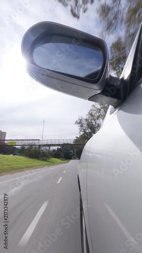 Driving SUV / car through city street / road - side mirror POV daytime. Vertical