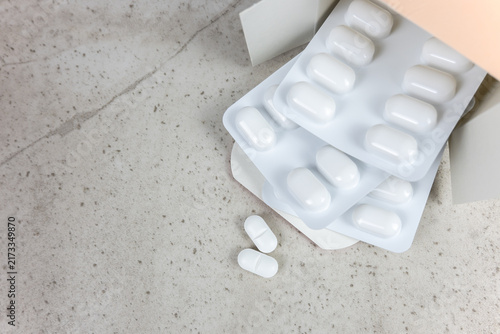 White pills and cardboard box on the stone background with place for text.