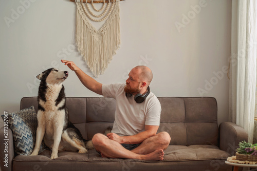 Fotografie Husky howling with its owner on a sofa at home
