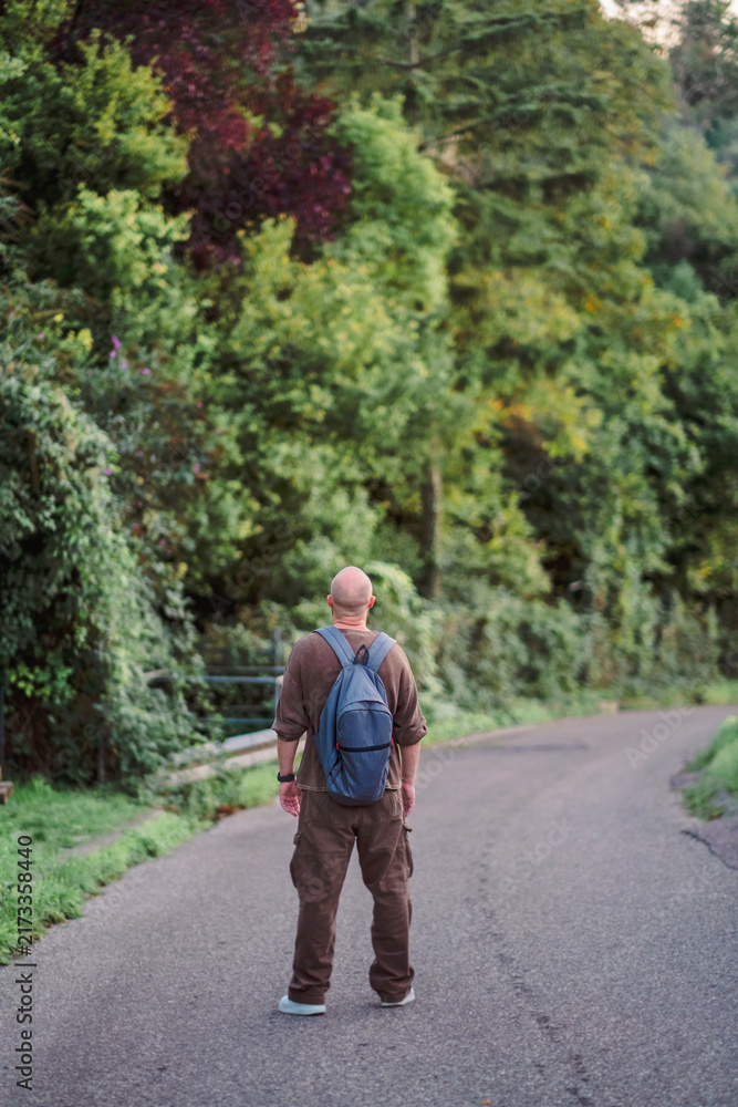 Fototapeta premium Rear view of a man standing alone on an empty country road