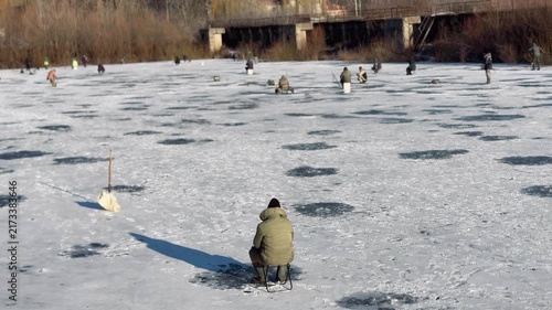 A fisherman fishes on ice during the winter season