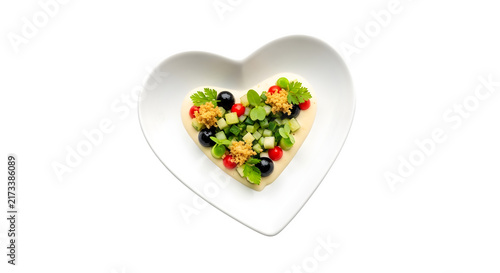 Heart shaped plate with fresh vegetable salad and hummus dip on a isolated transparent background for healthy eating and vegan nutrition