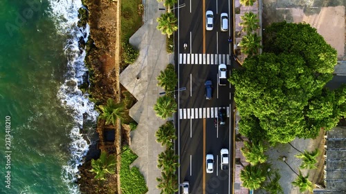 Aerial view of modern transport with expressway along the sea coast. Urban highway - view from above. Important infrastructure. Busy urban intersection. Oceanfront landscape. Cars in motion.