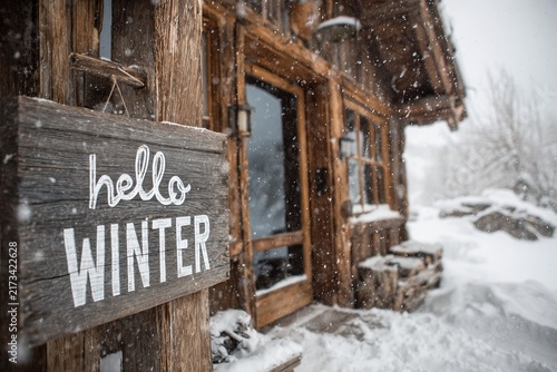 Charming winter cabin welcomes the season with snowy landscapes and a wooden sign inviting everyone to embrace the beauty of winter