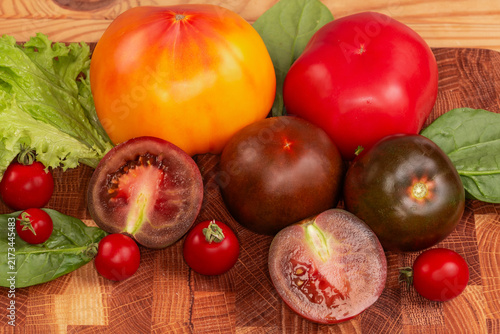Ripe tomatoes of different varieties on cutting board close-up
