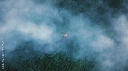 Car drives on rural road in the forest through Mist Over a Forested Mountain Valley
