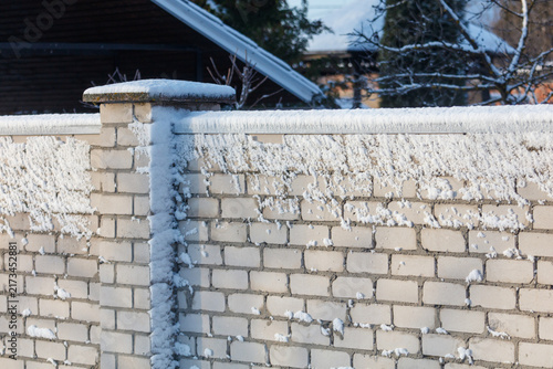 Frost clings to a snowy brick wall
