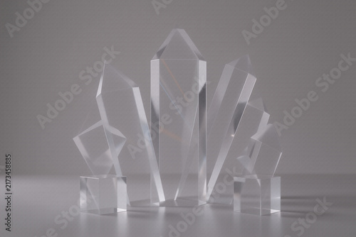 Abstract 3D render of glass crystal shapes on grey background for