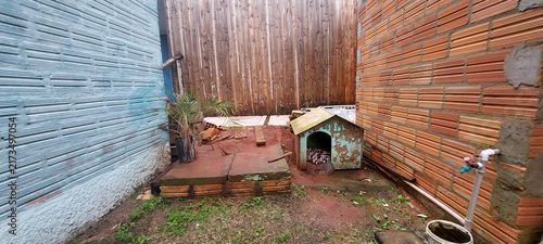 A doghouse with a nearby faucet in an enclosed yard.