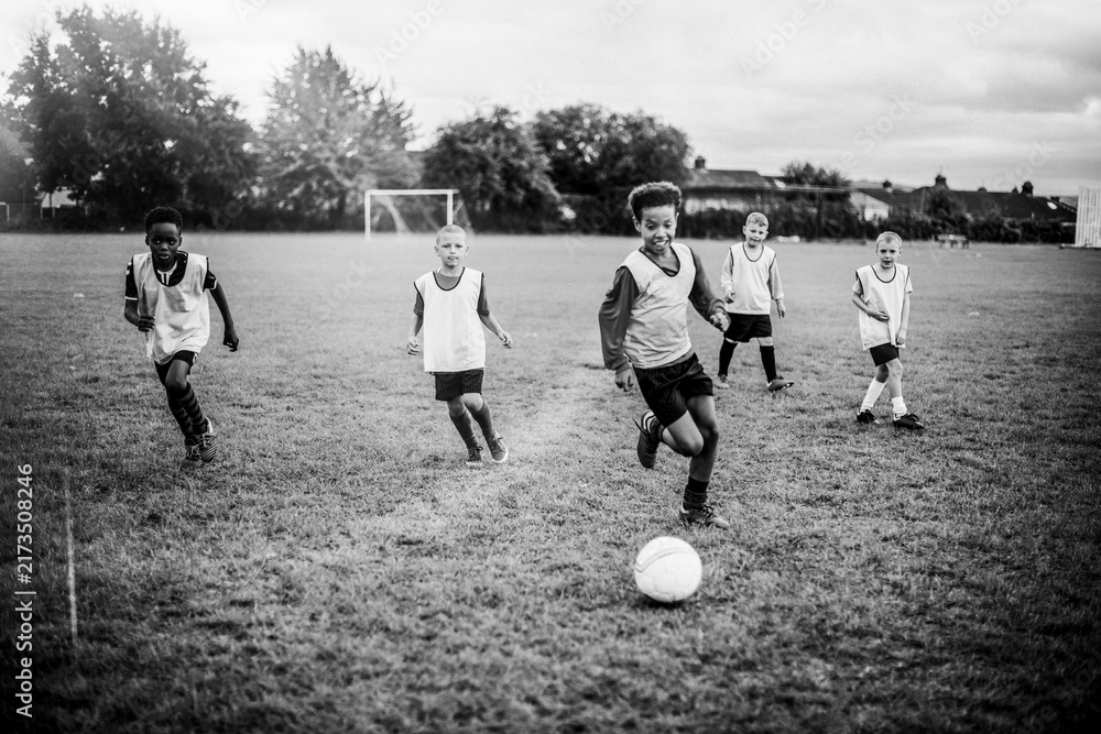 Fototapeta premium Children playing soccer on a grassy field in black and white