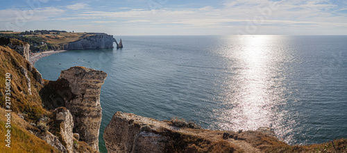 Vista panorámica aérea de la costa normanda de Etretat sobre el mar azul, con un arco de piedra al fondo y rocas de tiza típicas de los acantilados en un atardecer de verano, viajando Francia 2022