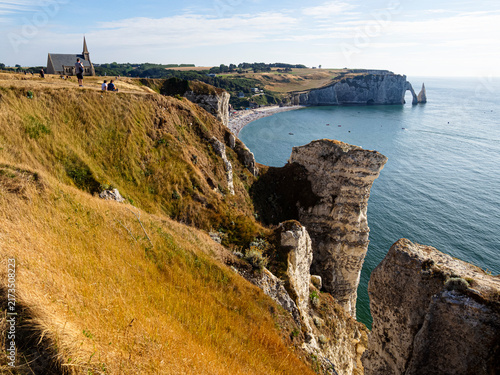Vista del arco y la iglesia desde los acantilados de la costa normanda en Etretat, Francia, paisaje característico de la costa sobre mar azul y formas singulares, viajando en verano 2022