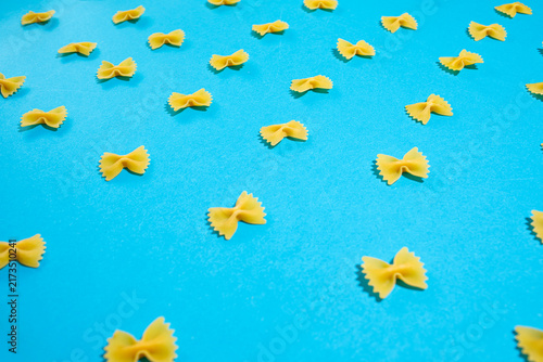 Quadro su tela Farfalle pasta bow ties scattered evenly across a vibrant blue background, creat