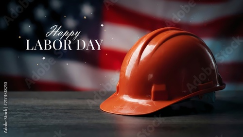 Happy Labor Day greeting with orange hard hat on wooden table. American flag background for Labor Day celebration. Construction safety helmet for national holiday social media post.