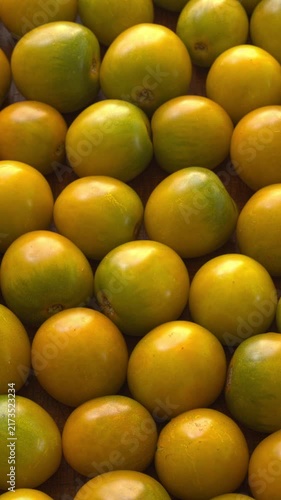 Green grape cherry tomatoes full frame background texture. Ripe homegrown, organic green heirloom tomatoes slowly rotating in a tight, high-angle top view with natural window light, vertical video.