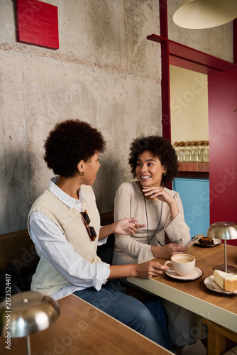 фотографія Two beautiful young African American women share joyful moments over coffee and dessert