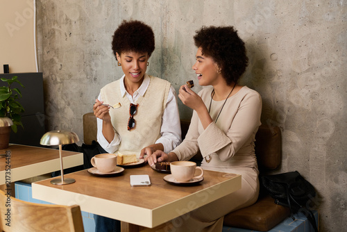 Принти на полотні Two young African American women share cake, coffee, laughter, and stories
