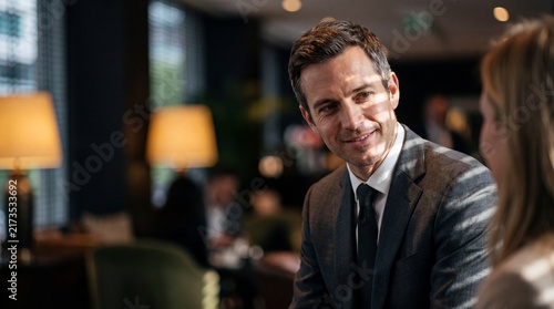 Handsome Businessman in Formal Suit Smiling During a Meeting in Modern Lounge