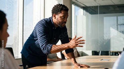 Confident African American Businessman Leaning Over Conference Table Leading a Team Meeting in Modern Office