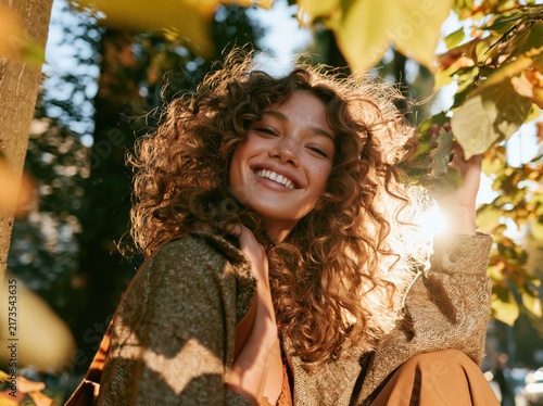 Smiling young woman with curly hair outdoors in autumn