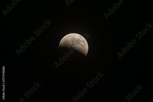 Konstfotografi Lunar eclipse phase illuminating the textured surface of the moon against the va