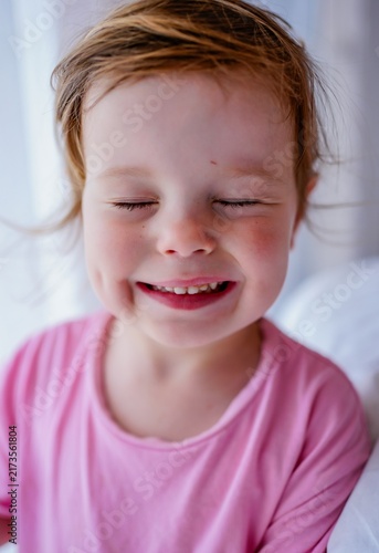 Cuadro en lienzo Happy little girl smiling with eyes closed at home