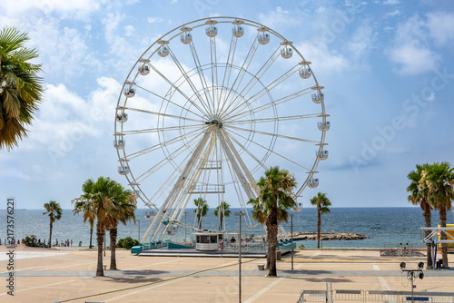 фотографія Seaside ferris wheel on the waterfront of an italian coastal city with palm tree