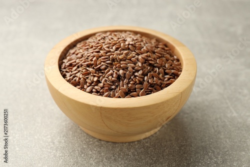 Flax seeds in bowl on grey table, closeup