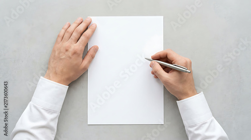 Top View of Male Hands Holding a Silver Pen Over a Blank White Sheet of Paper on a Grey Textured Background, Minimalist Business Mockup for Contract Signing and Creative Writing