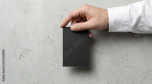 Businessman Hand Holding Blank Black Vertical Business Card Mockup on Grey Concrete Stone Texture Wall Background Professional Corporate Identity Branding Design Template for Portfolio Presentation