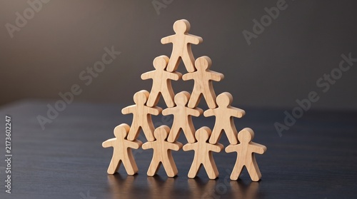Wooden human figures stacked in pyramid concept for teamwork, leadership, and corporate hierarchy structure