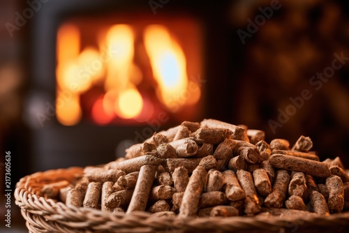 Pile of wood pellets in a wicker basket with a fireplace blurry in the background