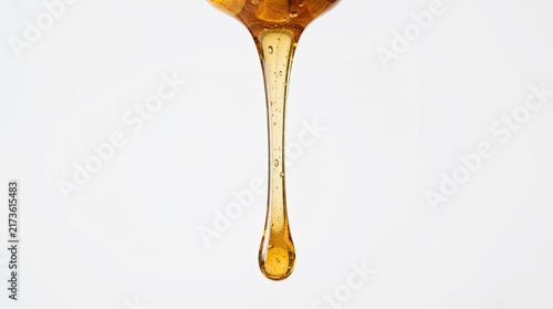 Golden Honey Dripping from Spoon Macro Shot Isolated on White Background