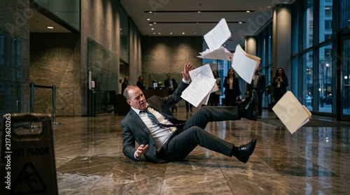 Businessman Slipping and Falling on Wet Floor in Corporate Office Lobby with Flying Papers