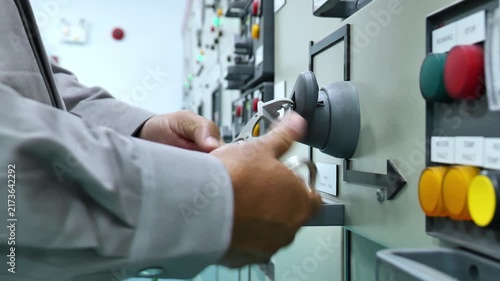 Professional electrician using electrical testing equipment and applying a safety lock to a power panel, illustrating Lockout Tagout, electrical maintenance, hazardous energy control, and accident pre