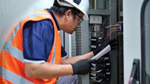 Professional engineer inspecting electronic equipment inside a fiber optic communication cabinet, checking digital signal transmission systems, network connections, optical devices, and advanced telec