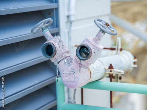 Foto Fire department connection standpipe with twin valves installed on the plumbing line near the building's ventilation louver