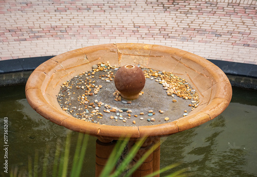Cuadro en lienzo Stone water fountain basin with a terra cotta pot and pebble rocks during exterior patio yard landscaping and architectural construction