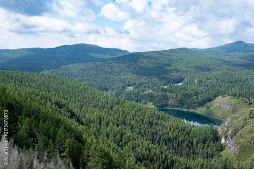 A mountain lake in a forested area on a summer day in cloudy weather
