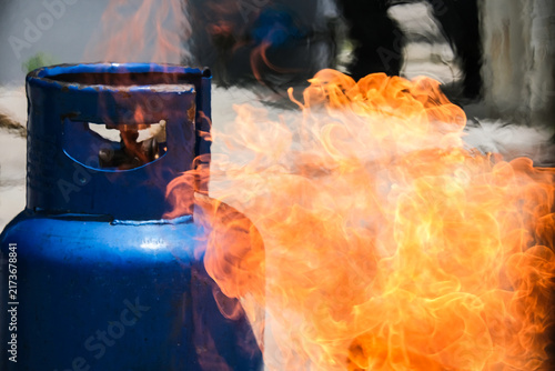 фотографія A dangerous fire and flames bursting out from a blue cooking gas cylinder, representing a fire hazard, industrial accident, and household safety emergency