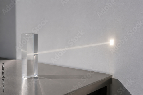 Sunbeam passing through clear acrylic block onto white wall, light transmittance concept
