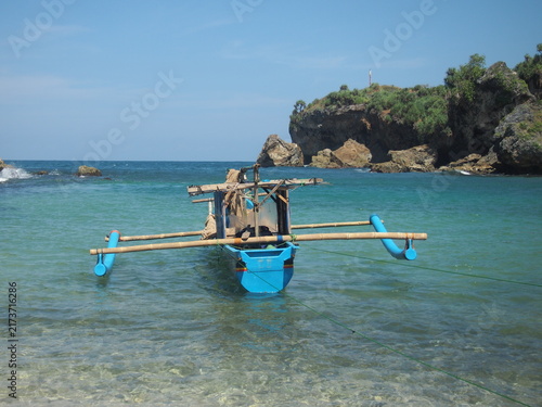 Foto A traditional blue outrigger fishing boat moored in the calm, clear waters of gu