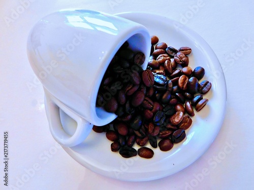 Принти на полотні White cup spilling roasted coffee beans on a saucer for a morning caffeine conce