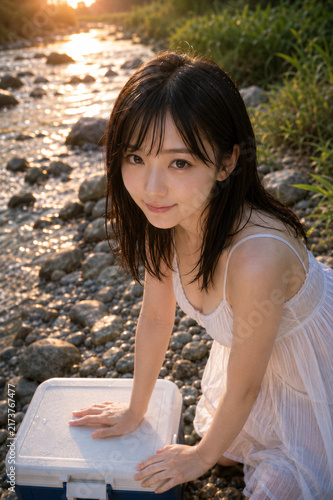 日本の夏の夕暮れの渓流で水遊びする笑顔の若い女性