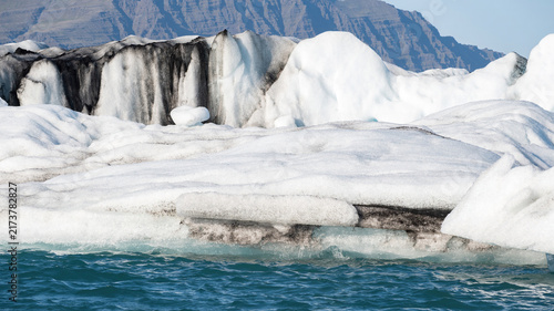 Foto A beautiful pile of ice fragments from Vatnajokull glacier floating along the shore of Jokulsarlon lagoon, Iceland, in a peaceful summer landscape