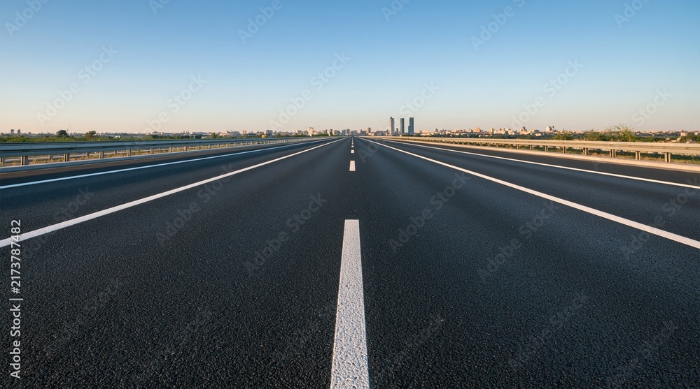 Fototapeta premium Empty asphalt highway leading to distant city skyline