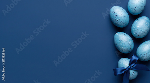 Blue speckled Easter eggs with ribbon on dark blue background