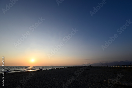 People enjoying sundown at tuscany beach. Togetherness at italian beach. Marina di Torre del LAgo, Tuscany, Italy, Europe.